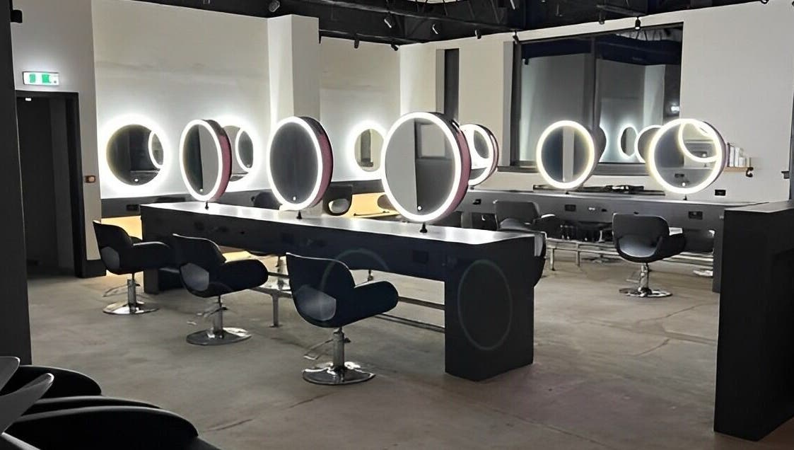 Modern salon interior at Calum Maguire Hairdressing, Ayr, Scotland, GB with sleek chairs and illuminated mirrors.