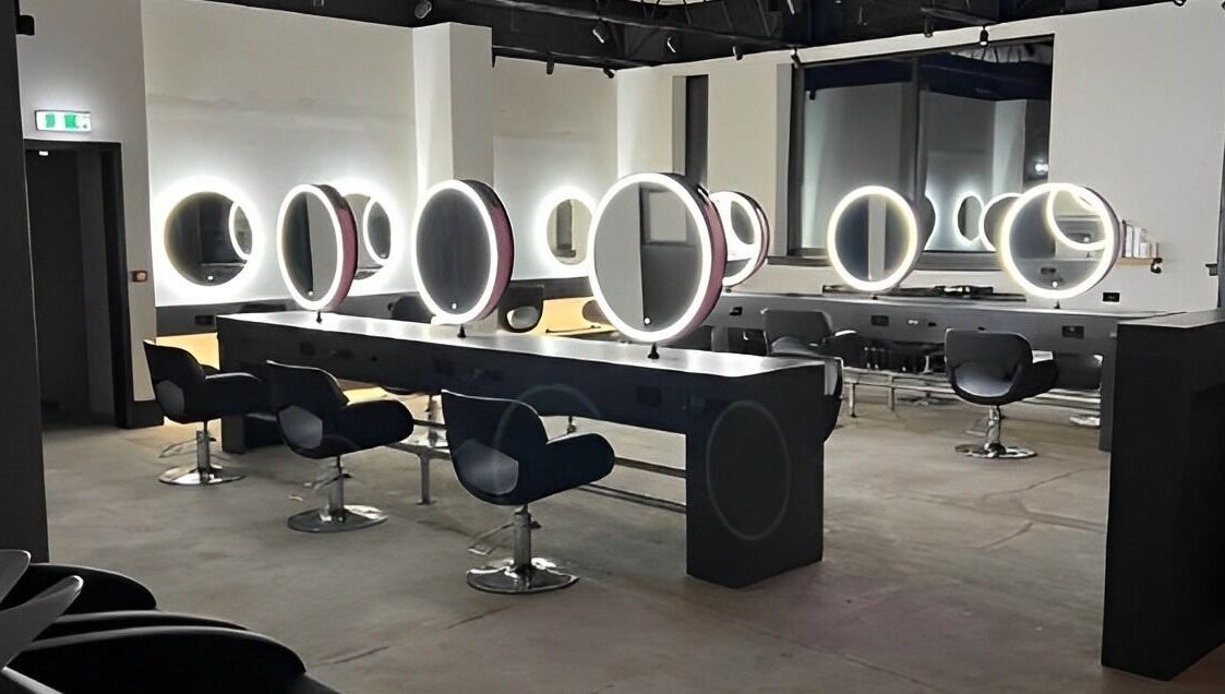 Modern salon interior at Calum Maguire Hairdressing, Ayr, Scotland, GB with sleek chairs and illuminated mirrors.