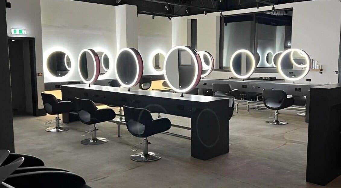Modern salon interior at Calum Maguire Hairdressing, Ayr, Scotland, GB with sleek chairs and illuminated mirrors.