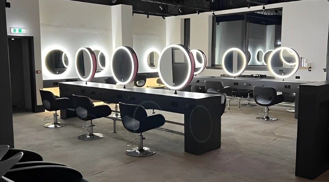 Modern salon interior at Calum Maguire Hairdressing, Ayr, Scotland, GB with sleek chairs and illuminated mirrors.