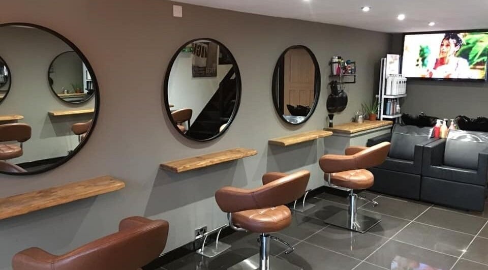 Modern salon interior at Calum Maguire Hairdressing in Ayr, Scotland, GB, featuring stylish chairs and mirrors.