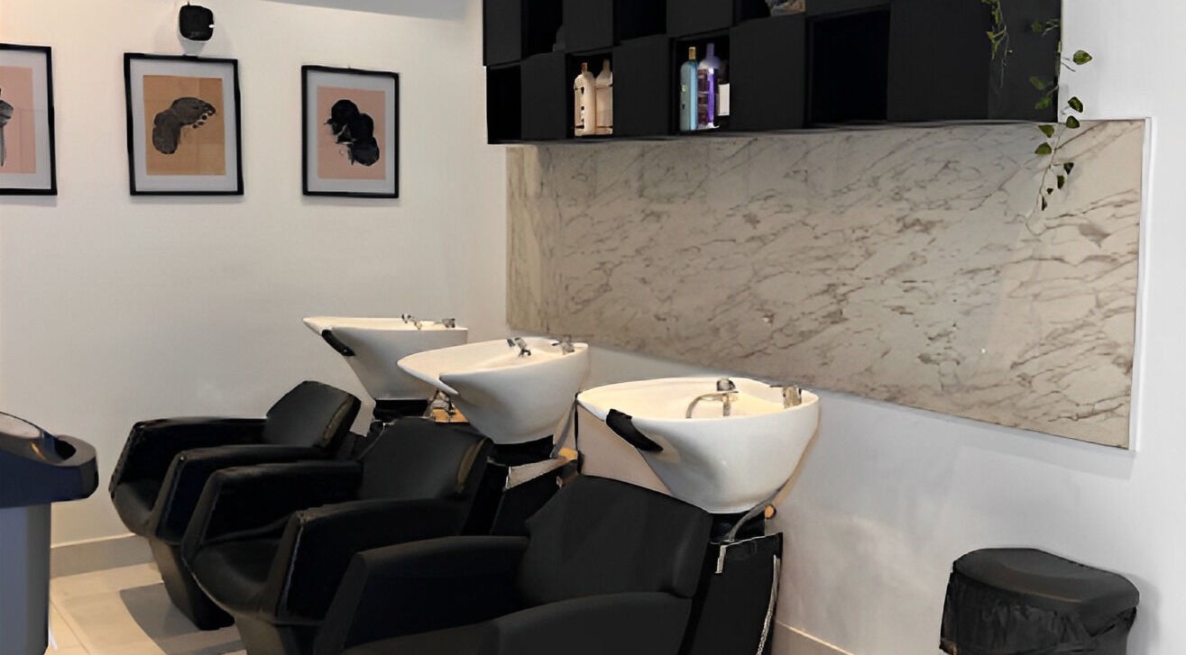 Modern wash stations at The Braiding Vault, Lekki, Lagos, NG elegantly designed with black chairs and marble accents.