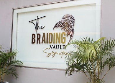Entrance sign of The Braiding Vault Signature, Lagos, Lagos, NG surrounded by lush green plants.