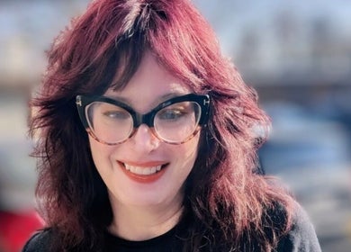 Smiling individual outside Rockin Rollers, Sierra Madre, California, US, showcasing stylish eyeglasses.