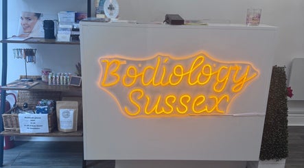 Bright neon sign of Bodiology Sussex at the reception in Eastbourne, England, GB showcases welcoming aesthetics.