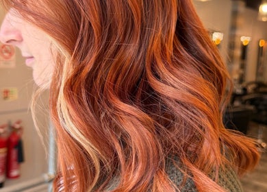Vibrant red hair styled at Erin McQuitty Hair, located in Carrickfergus, England, GB. Modern salon interior.