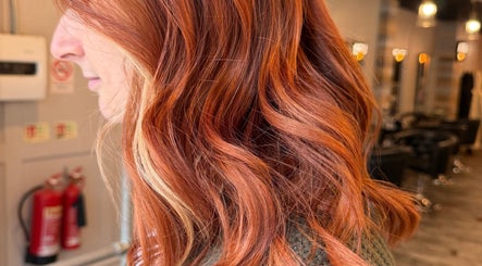 Vibrant red hair styled at Erin McQuitty Hair, located in Carrickfergus, England, GB. Modern salon interior.