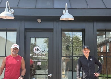 Two fitness trainers outside 541 William St., Fredericksburg, Virginia, US, smiling at the entrance.
