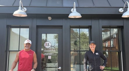 Two fitness trainers outside 541 William St., Fredericksburg, Virginia, US, smiling at the entrance.