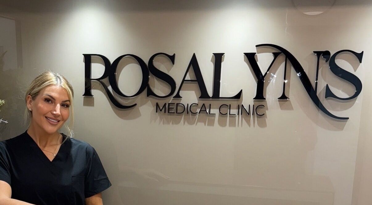 Smiling staff at Rosalyn’s Medical Clinic in Wakefield, England, GB, with clinic signage in background.