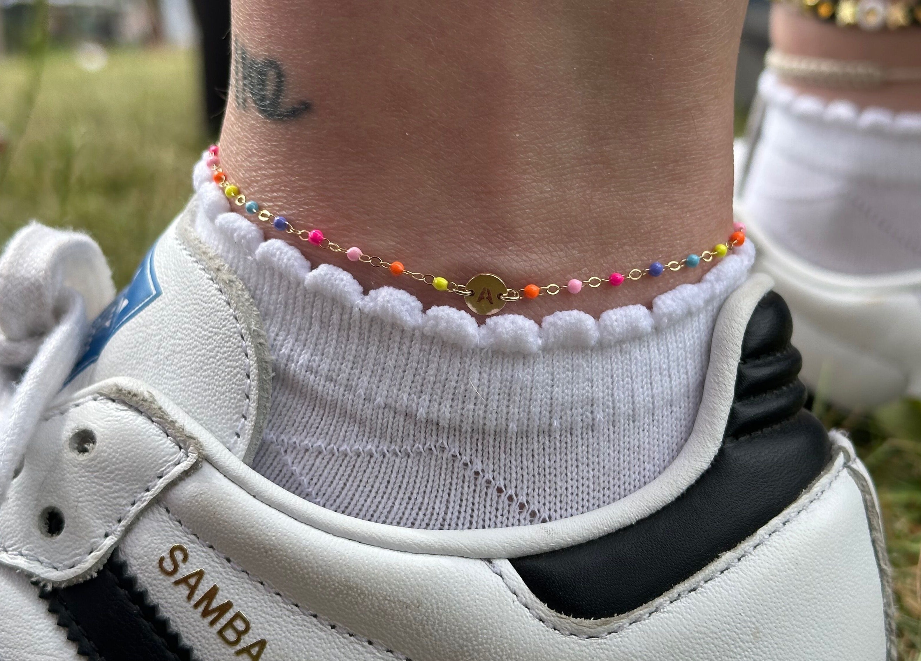 Colorful anklet over white sock and sneaker at Sanctuary Eleven-Daisy Chains, Royal Leamington Spa, England, GB.