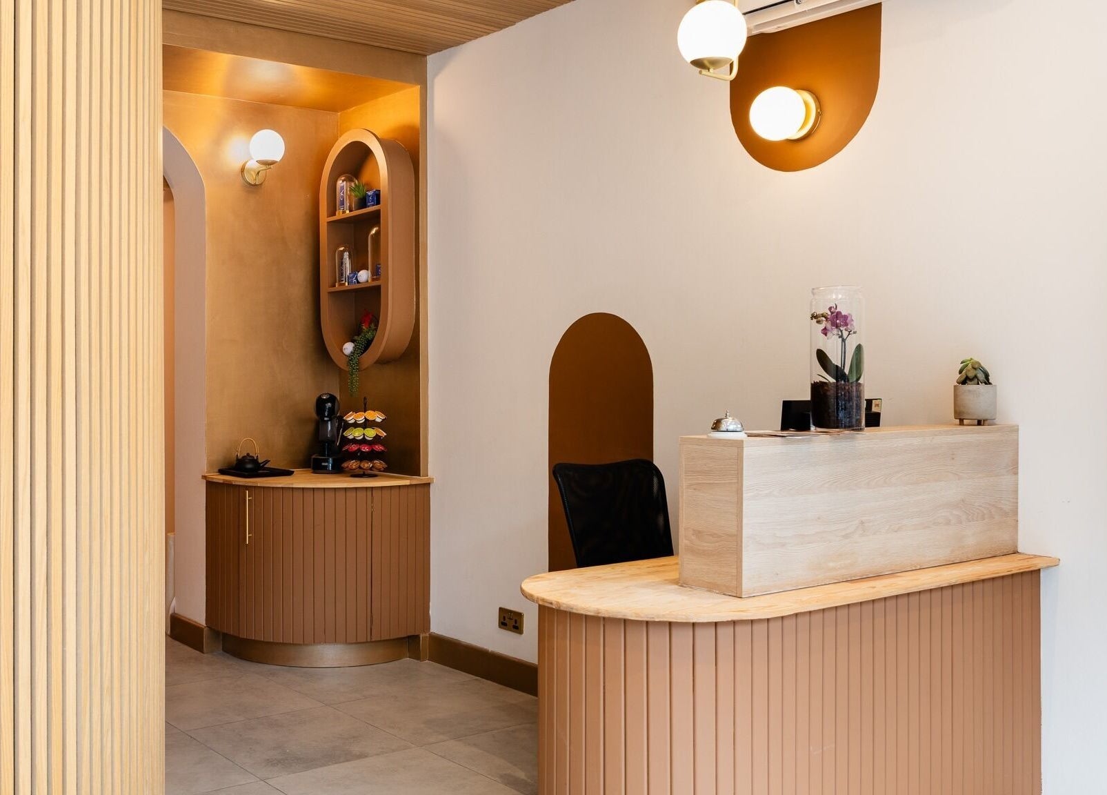 Modern reception area at INIYA Aesthetics & Laser Clinic in Stanmore, England, GB, with elegant decor and warm lighting.