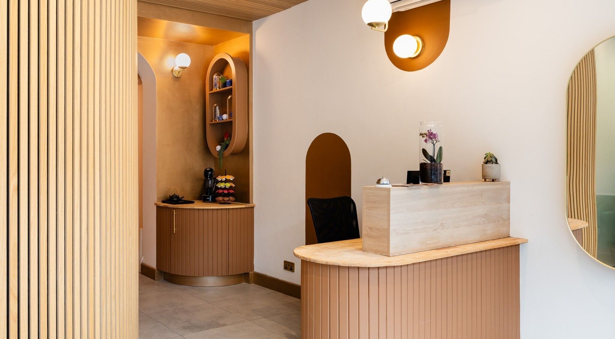 Modern reception area at INIYA Aesthetics & Laser Clinic in Stanmore, England, GB, with elegant decor and warm lighting.