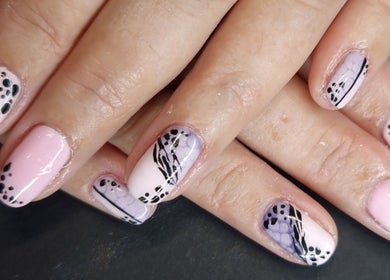 Elegant nail art at Inspired Nails in Northbourne, England, GB showcases intricate black and pink design.