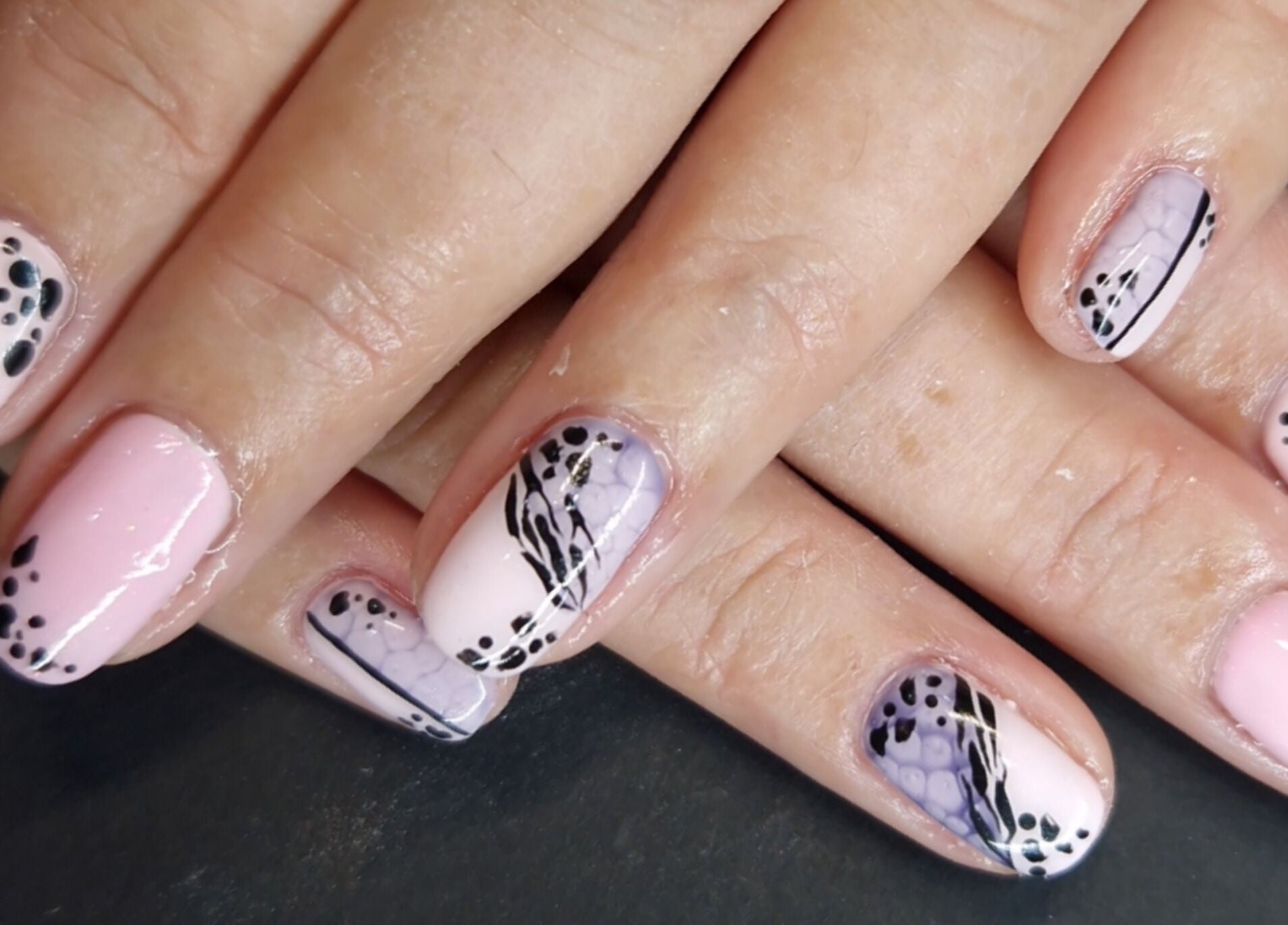 Elegant nail art at Inspired Nails in Northbourne, England, GB showcases intricate black and pink design.