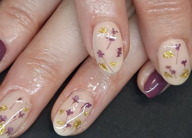 Intricate floral nail art at Inspired Nails, Northbourne, England, GB showcases purple and gold embellishments.