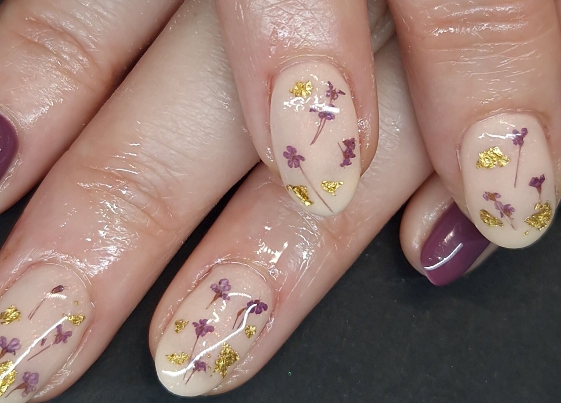 Intricate floral nail art at Inspired Nails, Northbourne, England, GB showcases purple and gold embellishments.