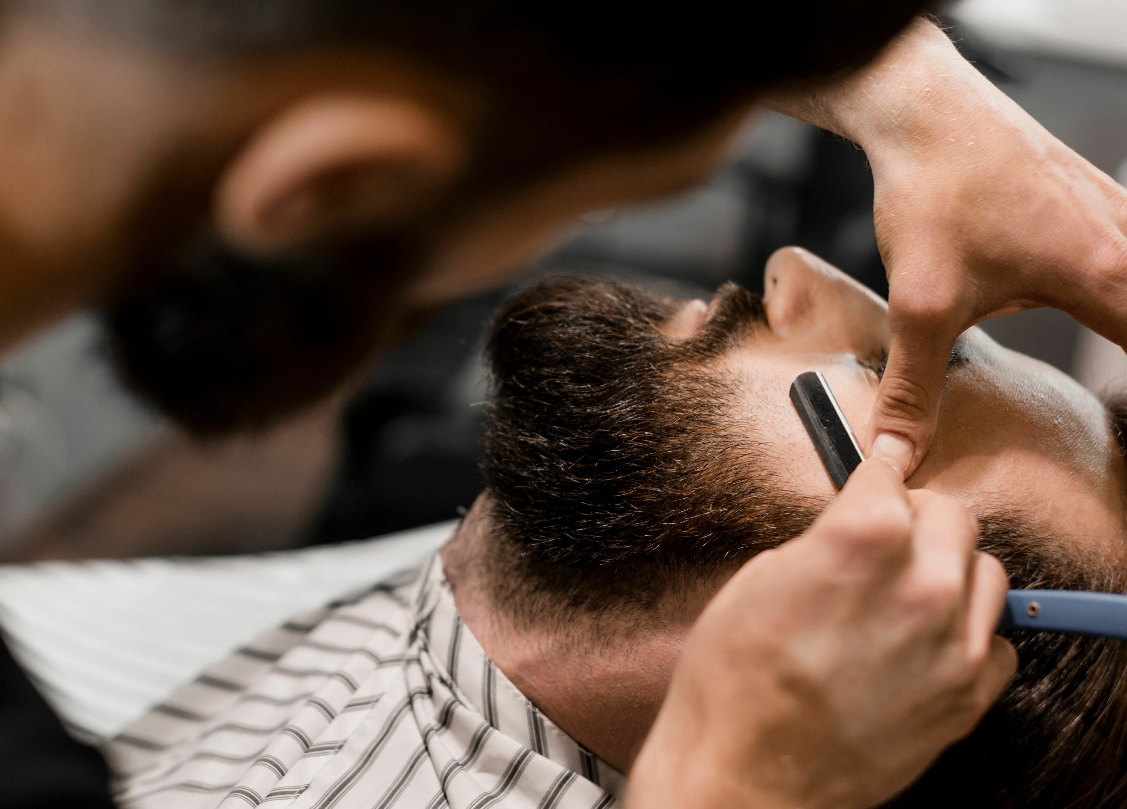 Expert beard shaving at Touches Men Salon in Dubai, Dubai, AE. Skilled barber using a straight razor.