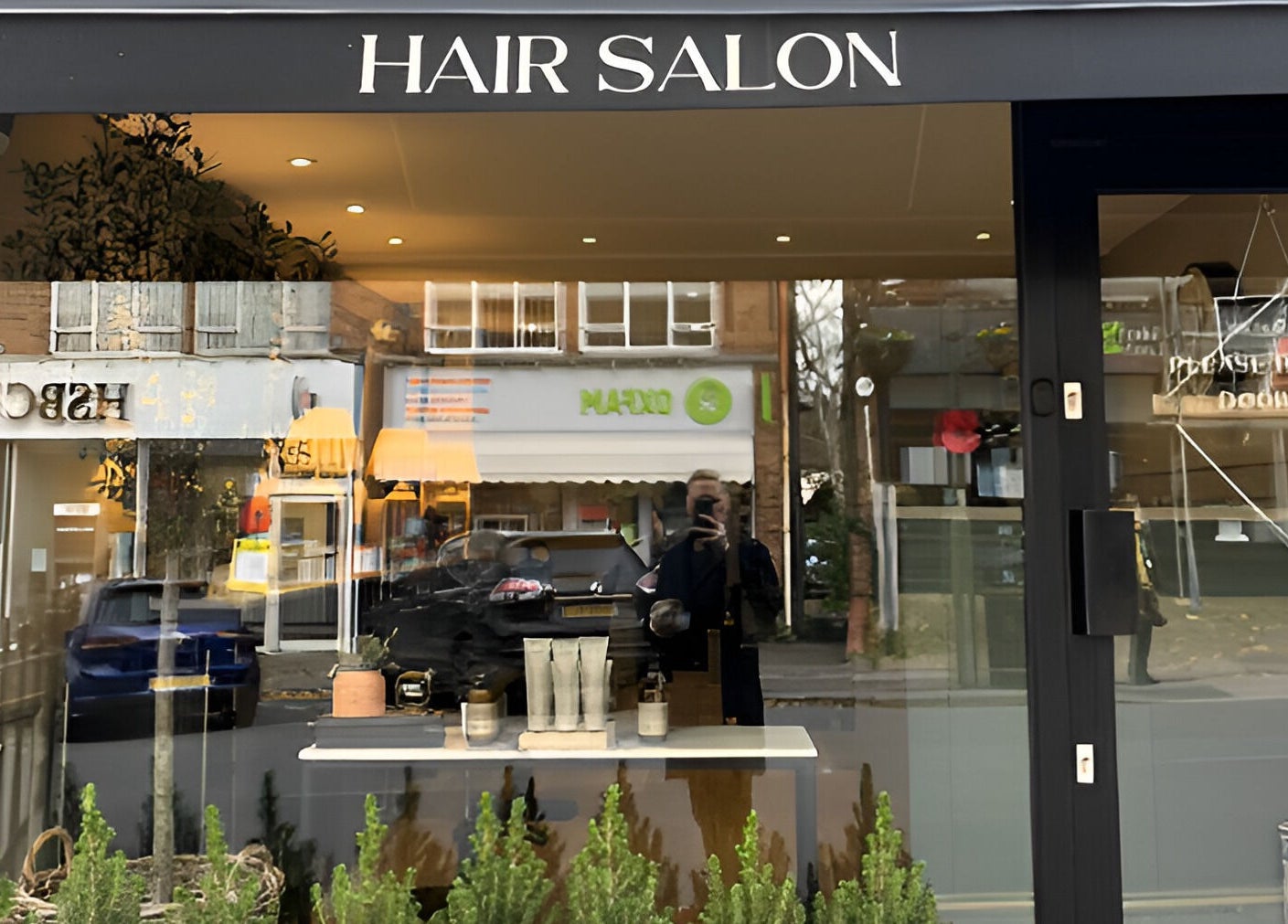 Front view of Adam James Oxted salon on Oxted High Street, England, showcasing modern beauty products.