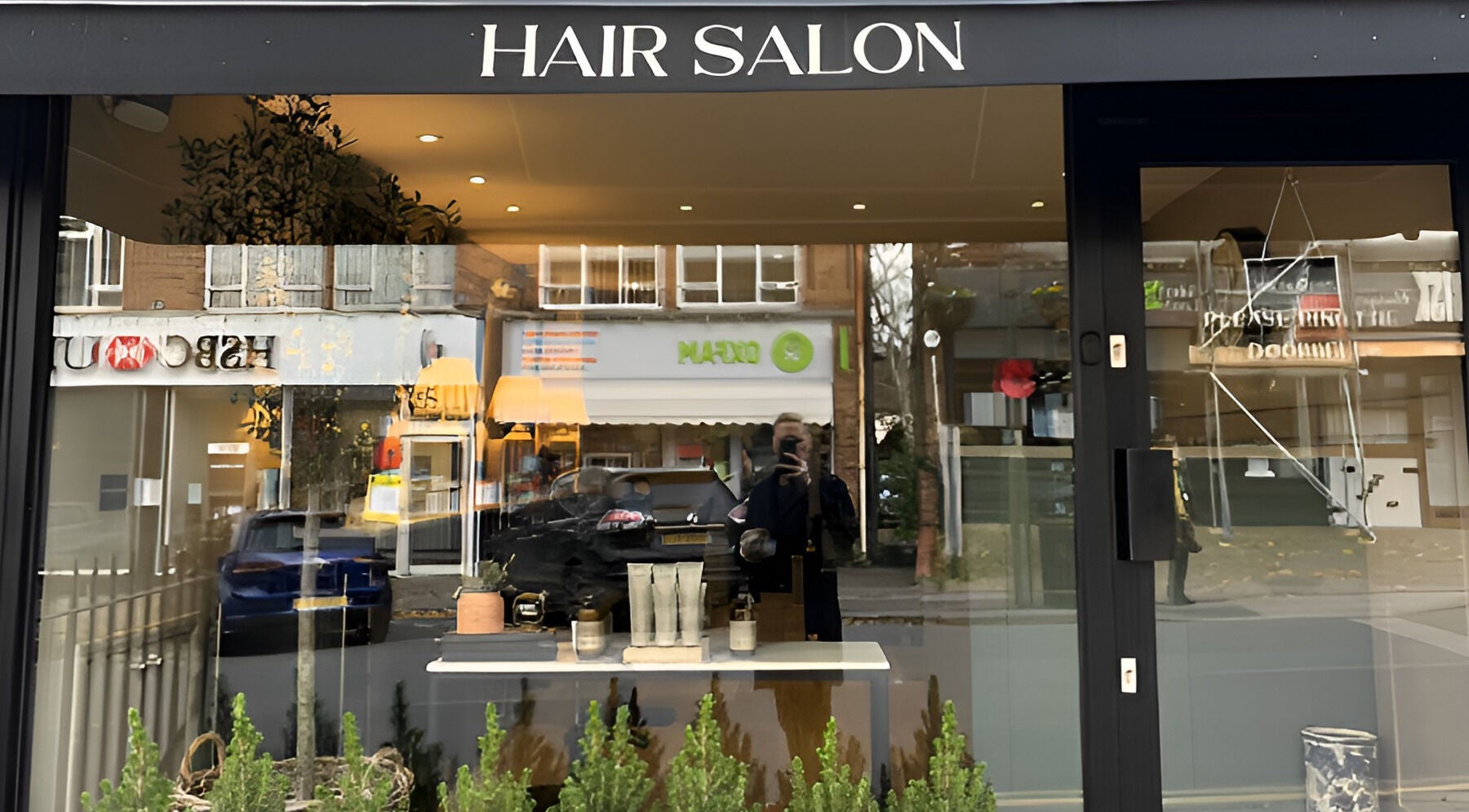 Front view of Adam James Oxted salon on Oxted High Street, England, showcasing modern beauty products.