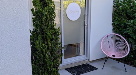 Entrance of My Beauty Treat, Woodend, Canterbury, NZ with a decorative chair and potted plants.