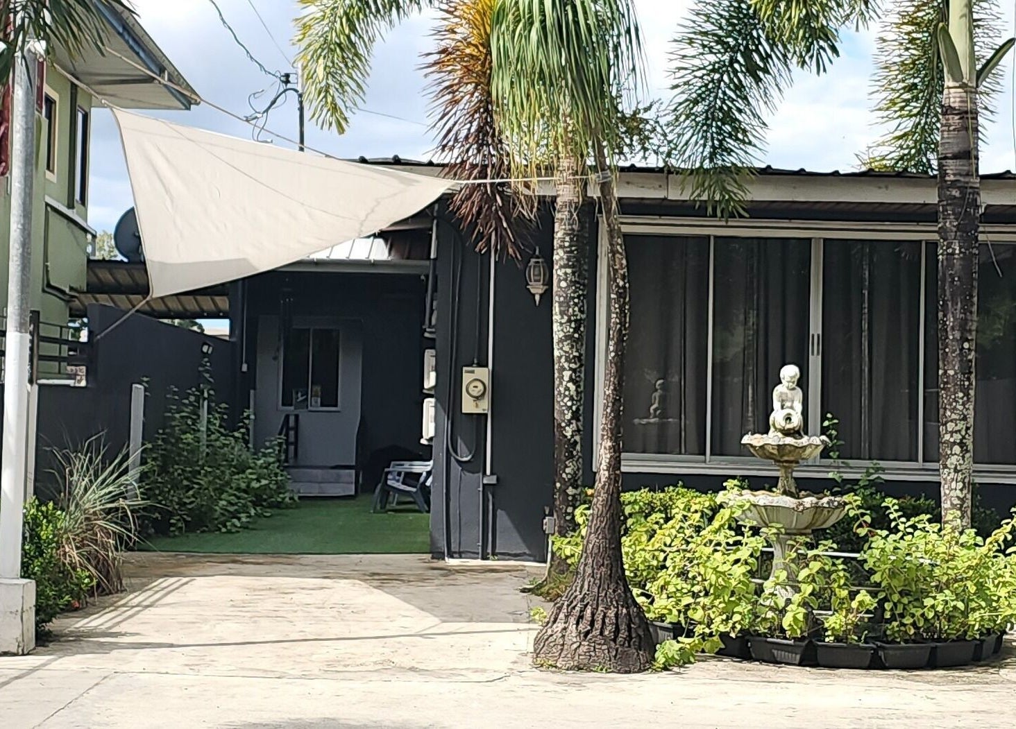 The DermLab entrance with palm trees and fountain at Freeport, TT, welcoming beauty and wellness seekers.