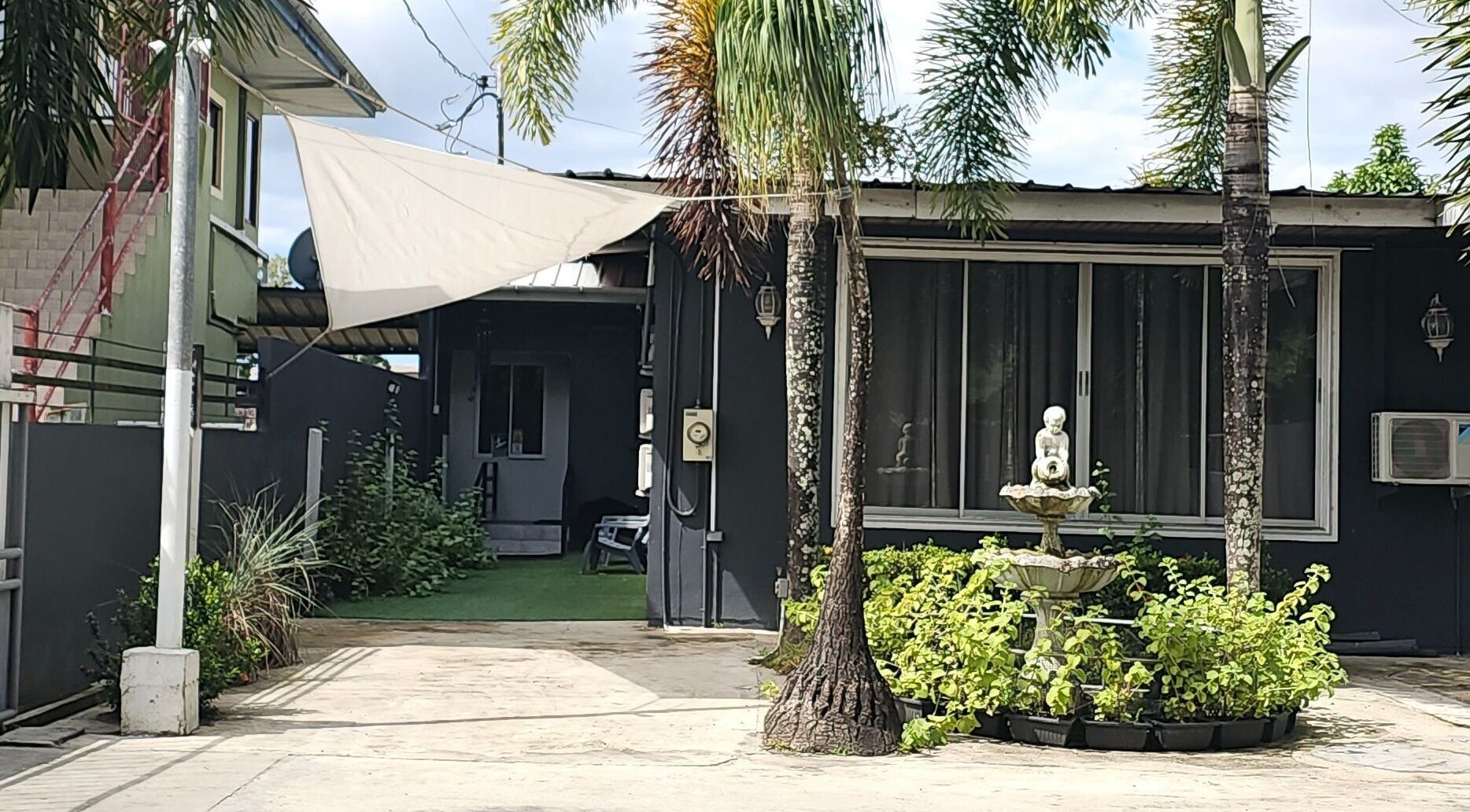 The DermLab entrance with palm trees and fountain at Freeport, TT, welcoming beauty and wellness seekers.