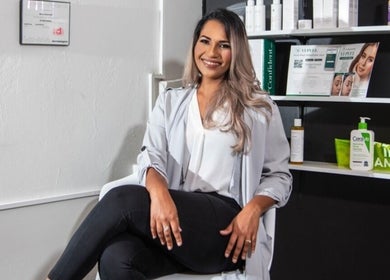 Smiling professional seated at The DermLab, Freeport, TT, enhancing customer care ambiance.