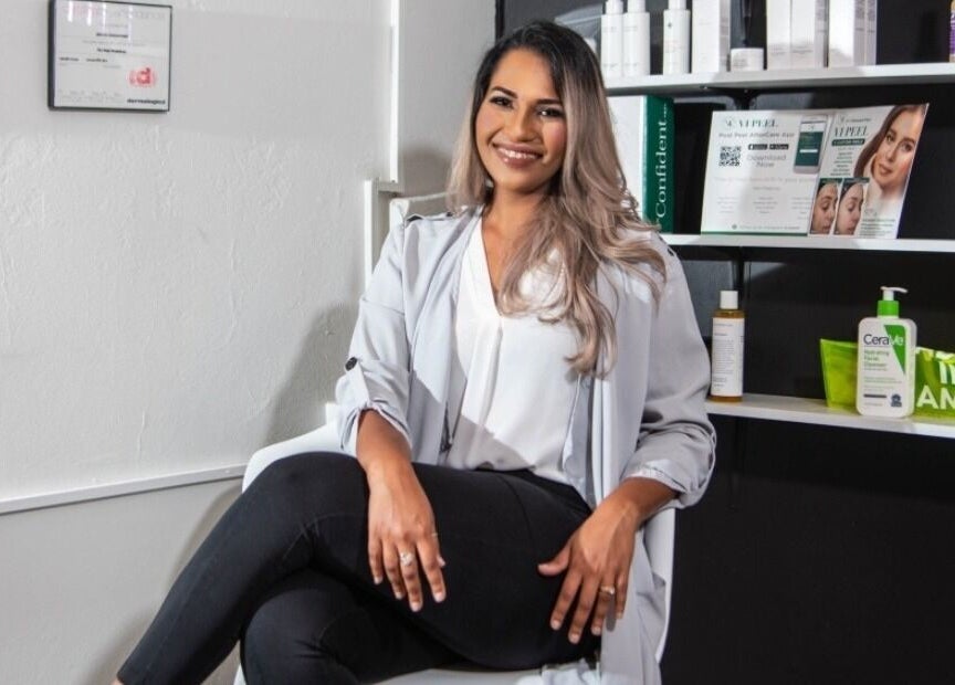 Smiling professional seated at The DermLab, Freeport, TT, enhancing customer care ambiance.