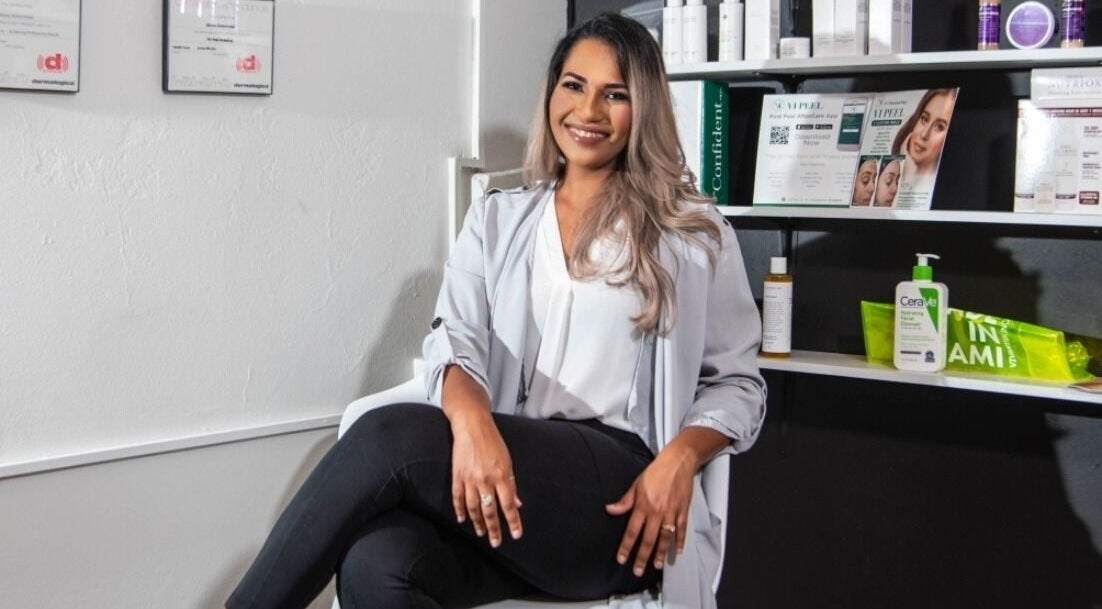 Smiling professional seated at The DermLab, Freeport, TT, enhancing customer care ambiance.