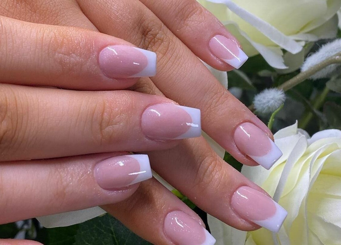 Flawless salon in Shaw, England, GB showcasing elegant French manicure on hands with white roses.