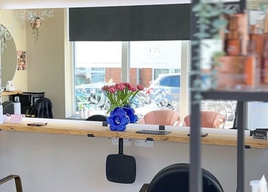 Interior view of Hairology Rushden salon in Rushden, England, featuring a stylish mirror and flower arrangement.