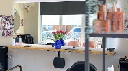 Interior view of Hairology Rushden salon in Rushden, England, featuring a stylish mirror and flower arrangement.