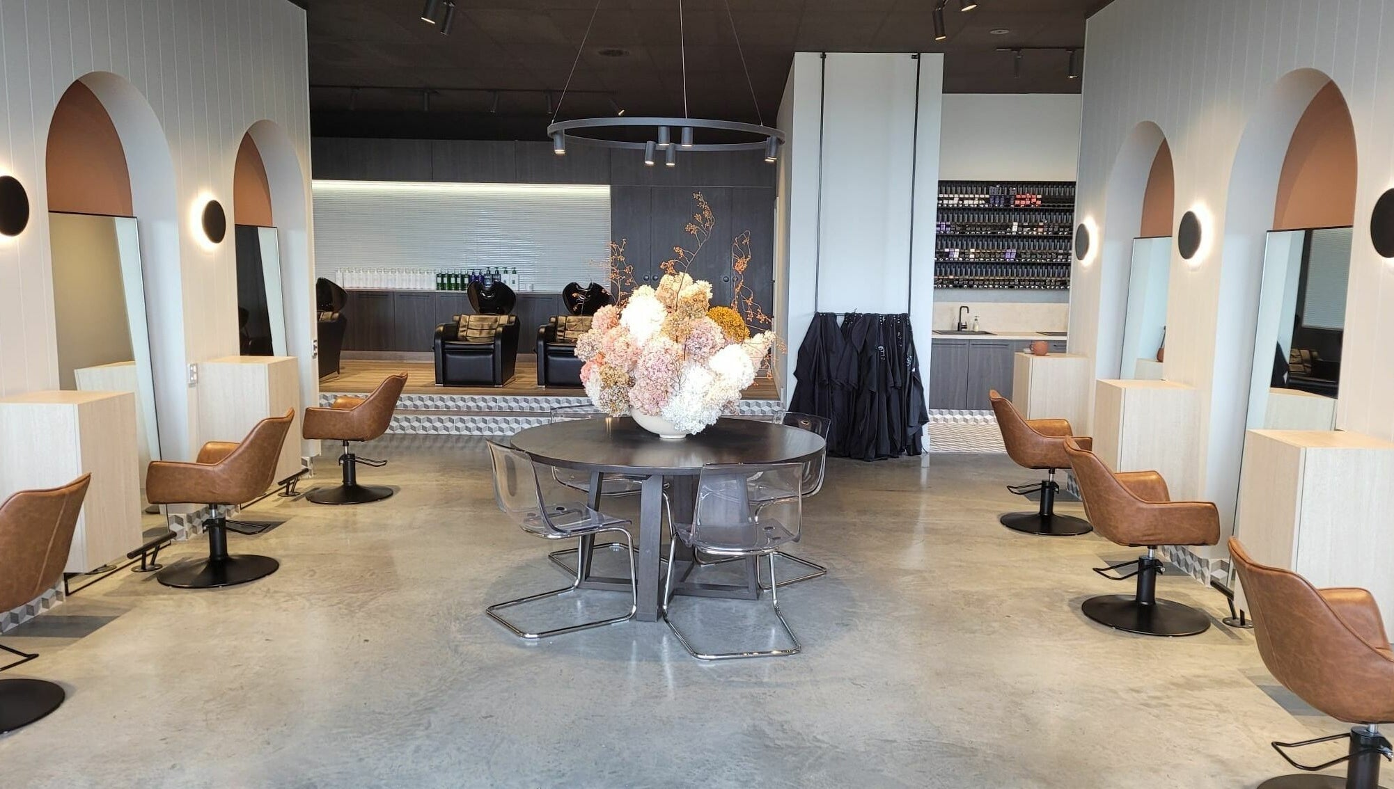 Chic interior of Unique Artist salon in Gledswood Hills, New South Wales, AU with sleek chairs and floral centerpiece.
