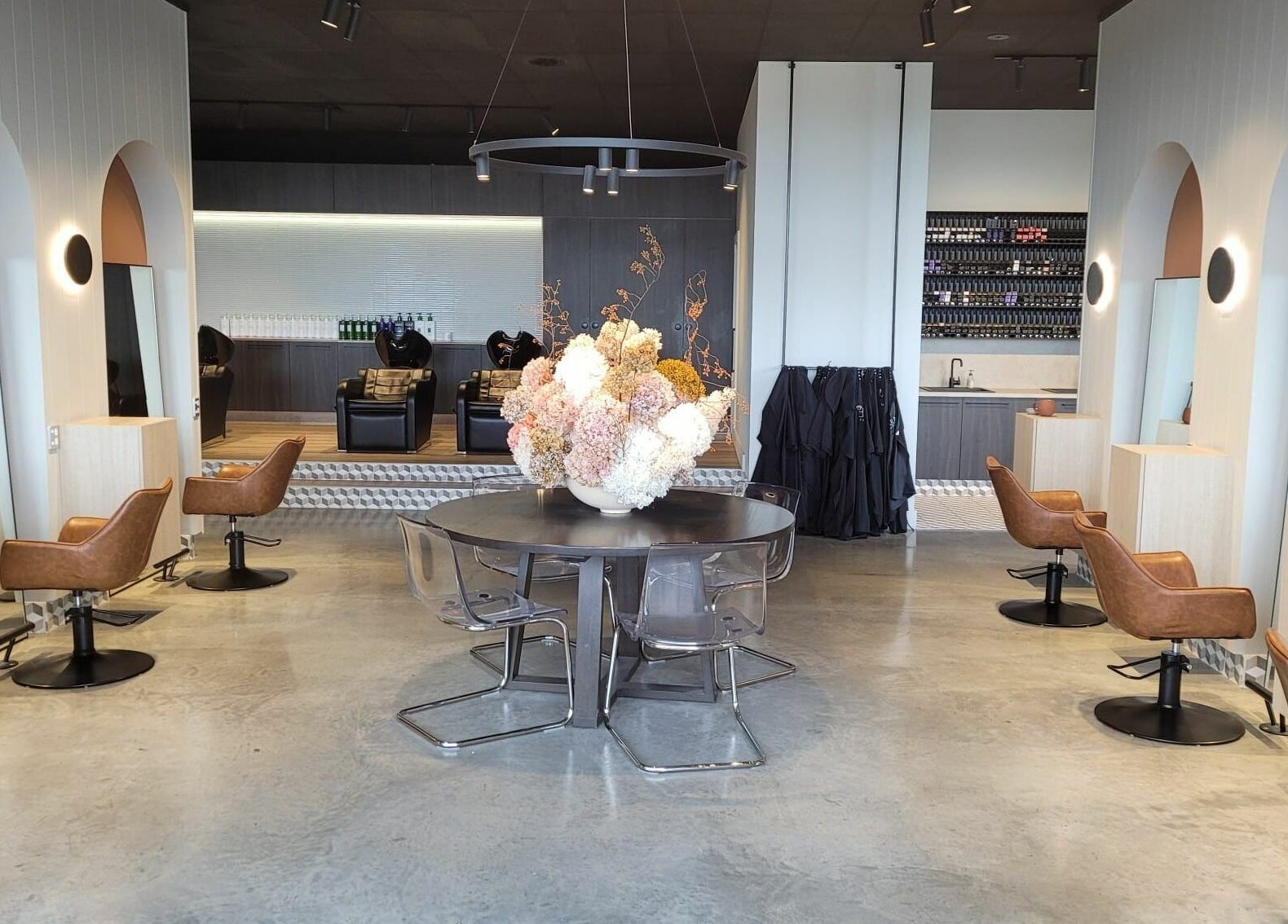 Chic interior of Unique Artist salon in Gledswood Hills, New South Wales, AU with sleek chairs and floral centerpiece.