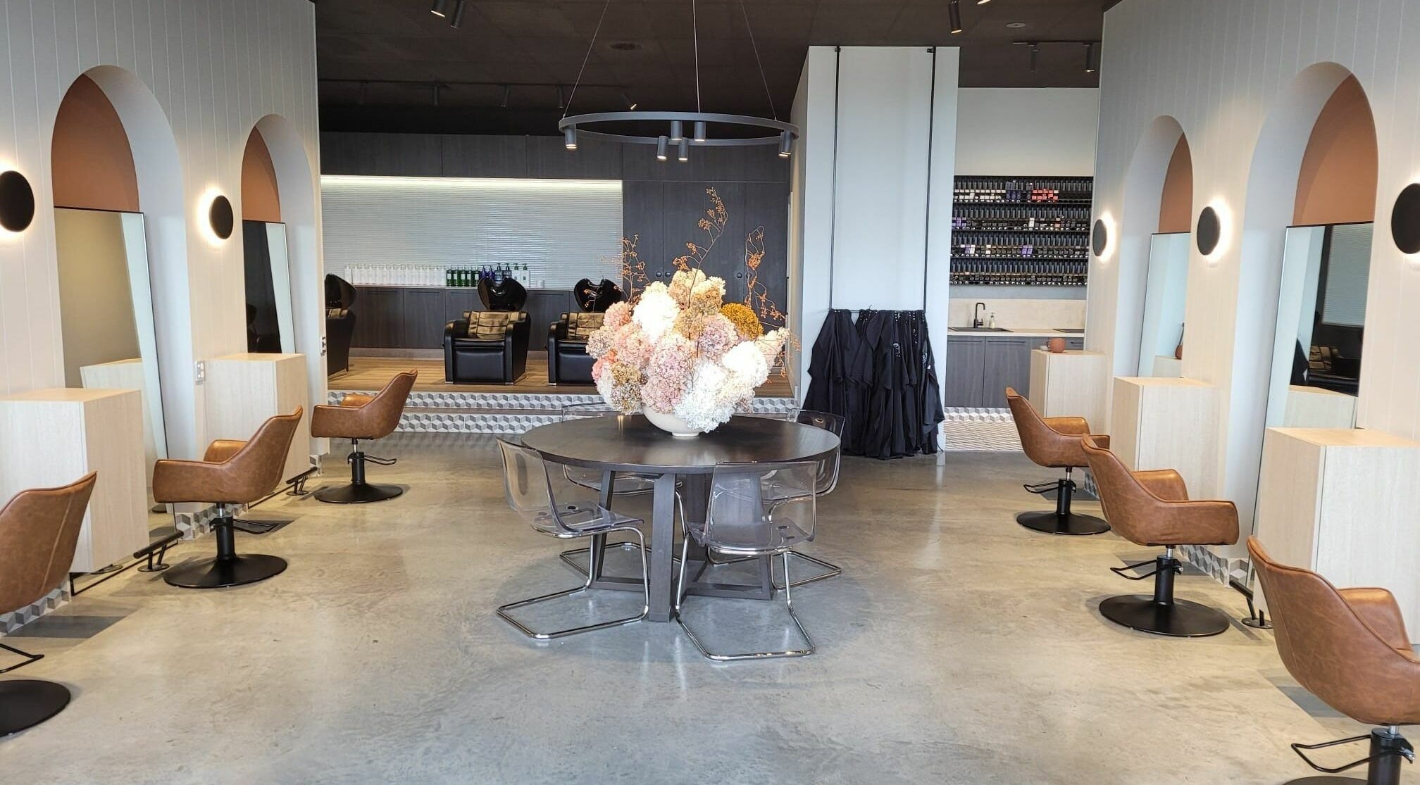 Chic interior of Unique Artist salon in Gledswood Hills, New South Wales, AU with sleek chairs and floral centerpiece.