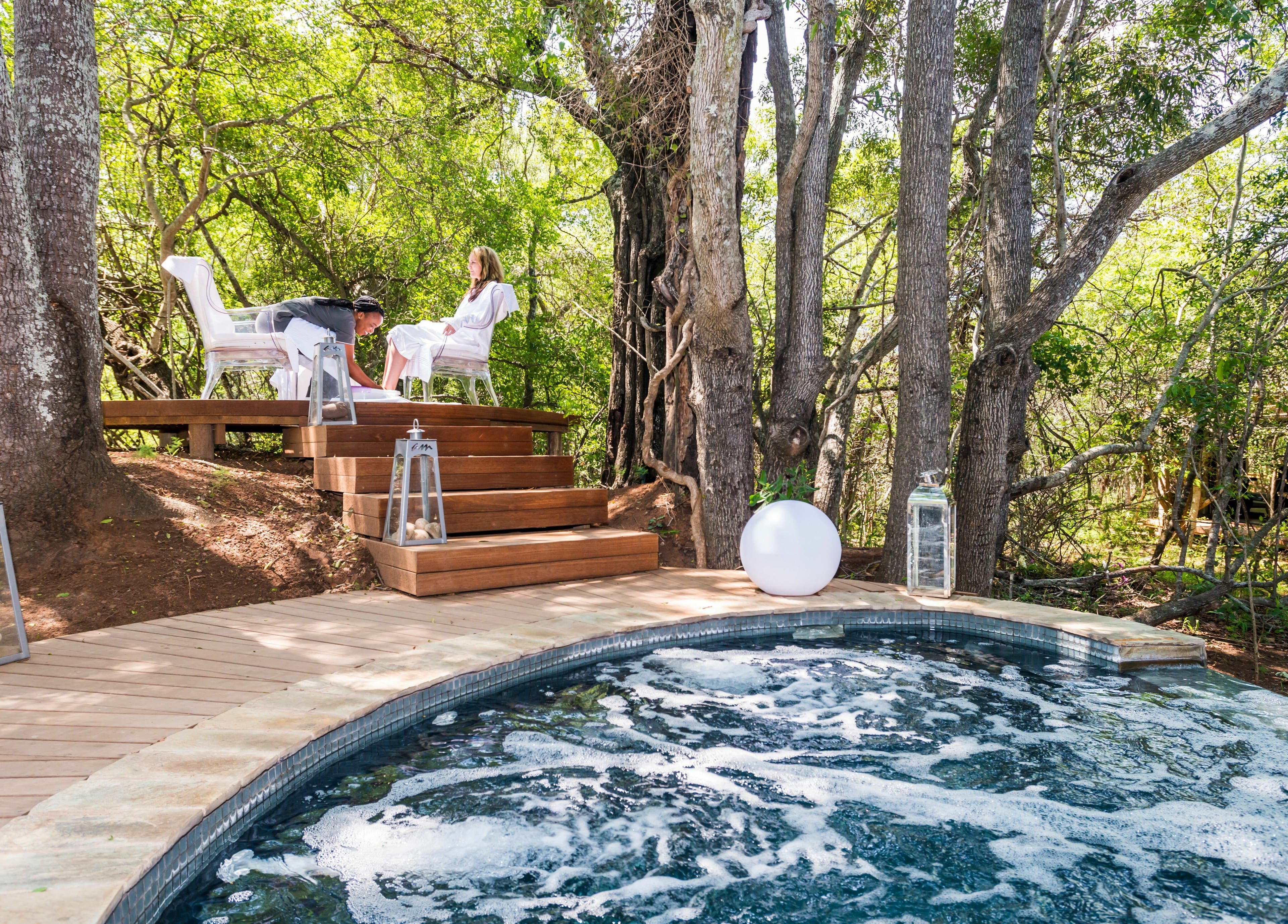Outdoor spa area at AM Spa Hoedspruit with lush trees in Hoedspruit, Limpopo, ZA, featuring a bubbling hot tub.