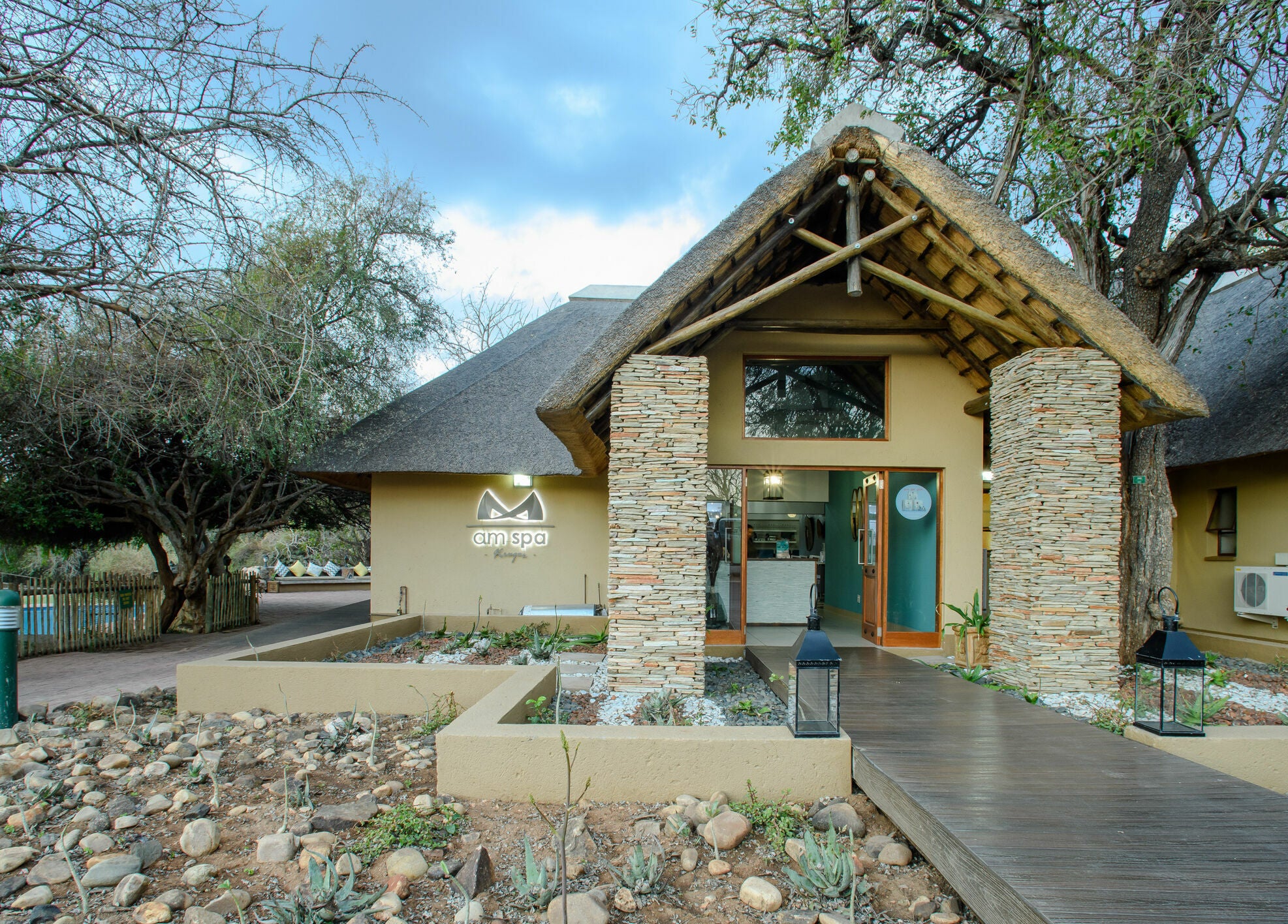 Front view of AM Spa Kruger in Skukuza, Mpumalanga, ZA with a rustic entrance and natural surroundings.
