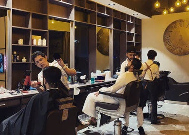 Stylish interior of Ak Barbershop (Mina Alarab), Al Jazirah Al Hamra, Ras al Khaimah, AE with barbers at work.