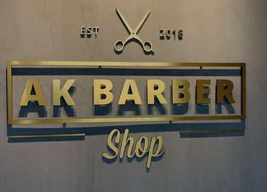 Gold-accented sign of Ak Barbershop (Mina Alarab), Al Jazirah Al Hamra, Ras al Khaimah, AE.