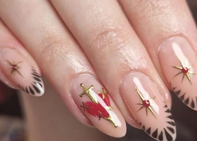 Intricate nail art at The Painted Parlour, Holmfirth, England, GB with red accents and gold details.
