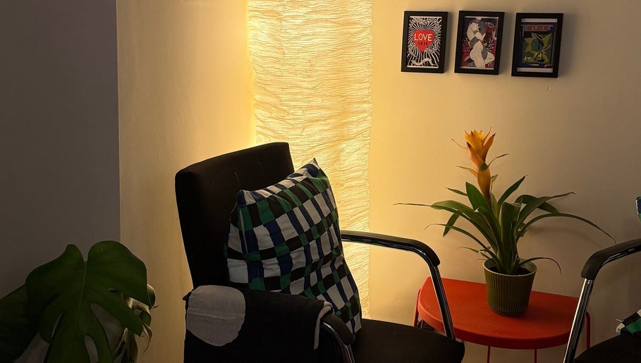 Relaxing chair, vibrant plant, and framed art at The Painted Parlour, Holmfirth, England, GB.