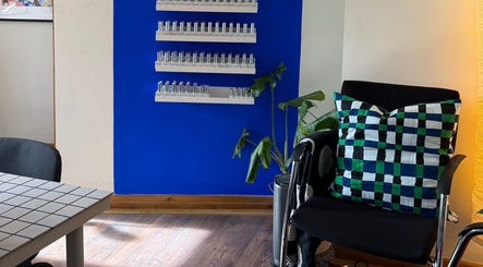 Elegant waiting area in The Painted Parlour, Holmfirth, England, GB with colorful decor and lush plant.