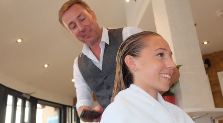 Stylist at Neil Curry Hairdressing Ltd, Cambridge, England, GB, attentively brushing a client's hair.