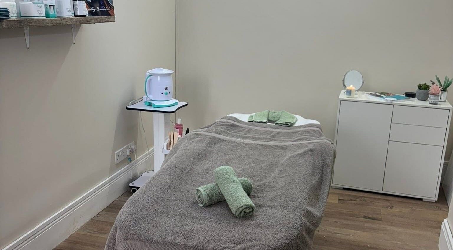 Relaxing treatment room at The Hive Beauty, Holistics & Hair in Cullompton, England, GB, with cozy massage bed.
