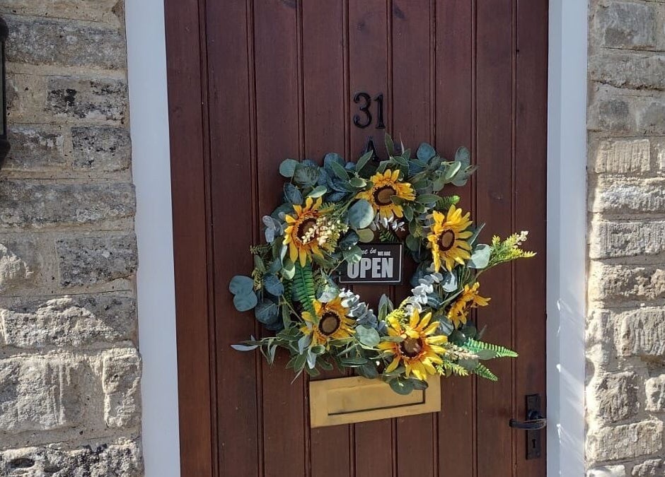 Entrance of Bavaro’s Hair Design Ltd with a sunflower wreath in Aldwincle, England, GB.