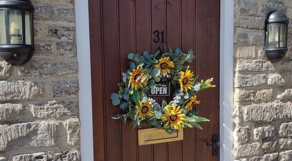 Entrance of Bavaro’s Hair Design Ltd with a sunflower wreath in Aldwincle, England, GB.
