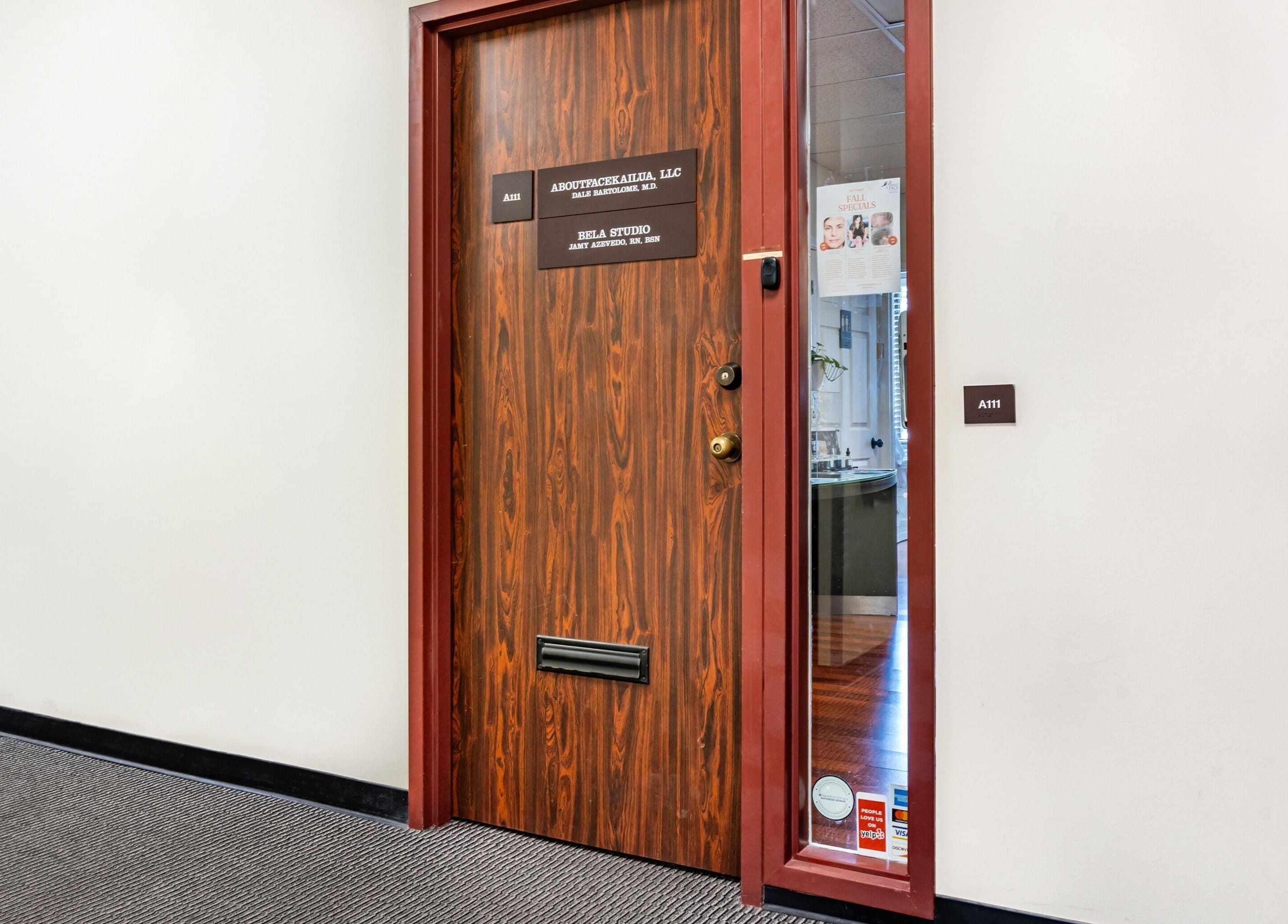 Entrance to Enhance Hawaii, Kailua featuring a wooden door with glass side panel.