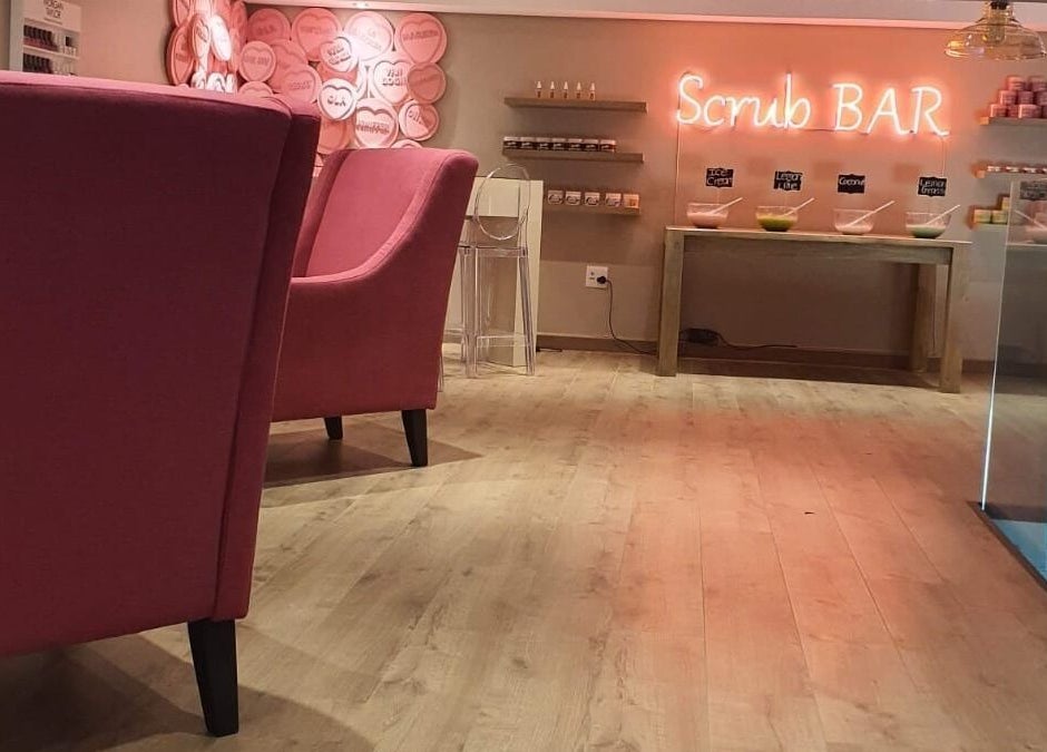 The Skin Revision Co's vibrant Scrub Bar in Centurion, Gauteng, ZA featuring plush pink chairs and a sleek display.
