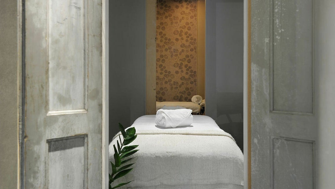 Knusse behandelkamer bij Spa Manda, Haarlem, Noord-Holland, NL, met rustieke deuren en zachte handdoeken.